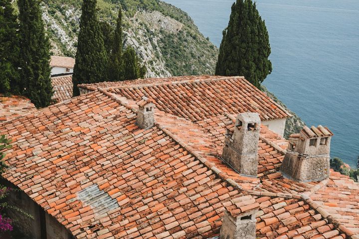 Toits de tuiles et cyprès au-dessus de la mer, dans un village perché de la Côte d'Azur