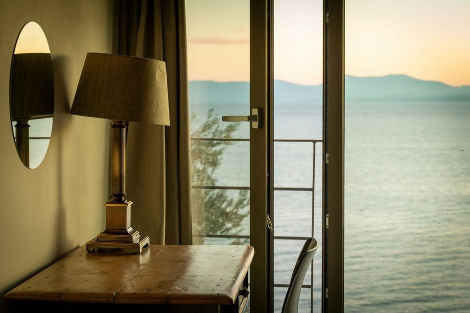 Lampe et table près d'une porte-fenêtre ouverte sur la mer, au soleil couchant